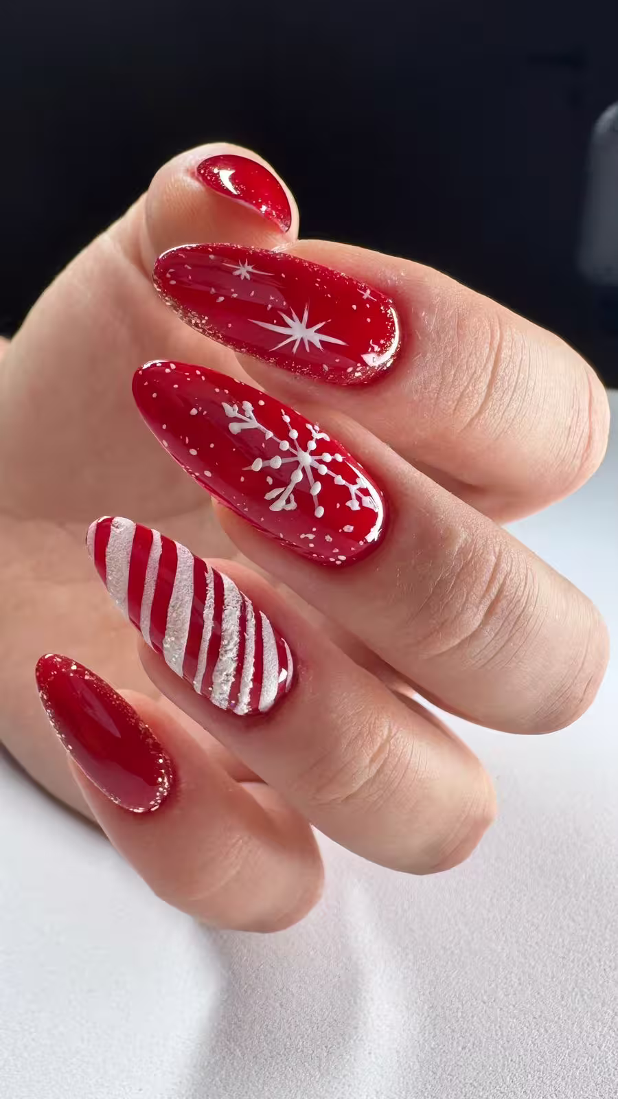 Festliche rote Mandelnägel mit Schneeflocken und Zuckerstangen-Design
